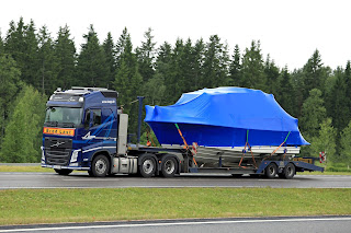 Paimio, Finland - June 23, 2016: Blue Volvo FH semi truck hauls a boat as exceptional load along freewa in South of Finland. Abnormal transport permit is required, if any dimension of the load exceeds the free dimension limits.